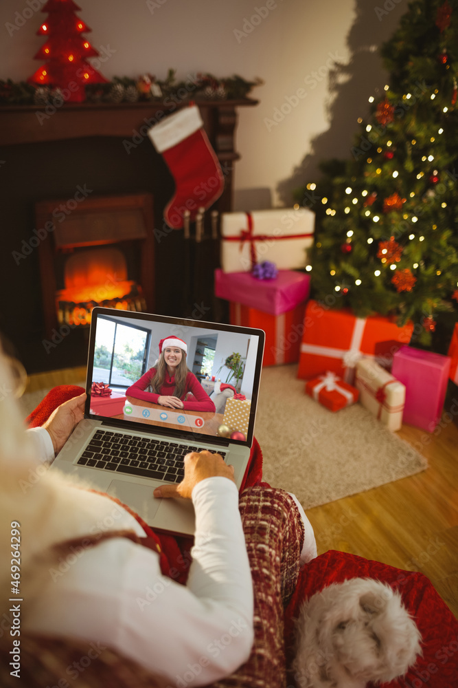 Poster Santa claus making laptop christmas video call with smiling caucasian woman in santa hat