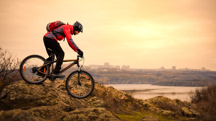 Fototapeta na wymiar Cyclist Riding the Mountain Bike on the Rocky Trail at Autumn Evening. Extreme Sport and Enduro Cycling Concept.