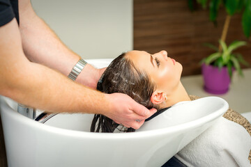 Obraz na płótnie Canvas Beautiful caucasian woman washing hair in a beauty salon