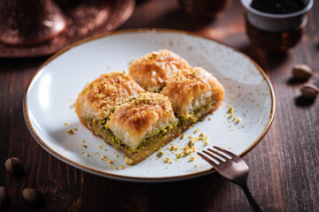 Turkish or Bosnian dessert called Baklava with pistachio served with traditional Turkish or Bosnian coffee set on a wooden board in moody atmosphere