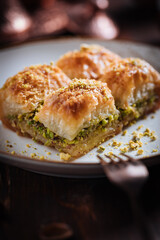 Turkish or Bosnian dessert called Baklava with pistachio served with traditional Turkish or Bosnian coffee set on a wooden board in moody atmosphere