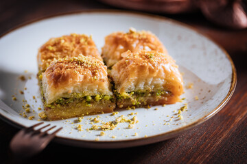 Turkish or Bosnian dessert called Baklava with pistachio served with traditional Turkish or Bosnian coffee set on a wooden board in moody atmosphere