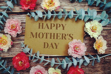 Happy Mother's Day text with flowers frame decorate on wooden background