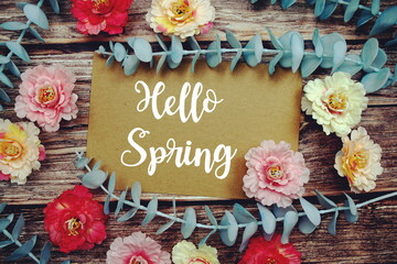 Hello Spring text with flowers frame decorate on wooden background