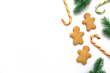 Christmas gingerbread cookies in the shape of man with lollipops and fir branches on white...