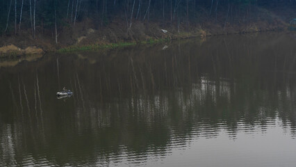 Fisherman in rubber boat on the river. Mature man fishing from the boat on the river at evening.