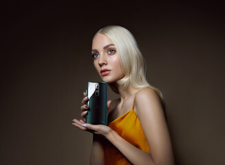 A young beautiful woman with blond hair holds a modern smartphone in her palm. Mobile phone advertising.Advertising concept.