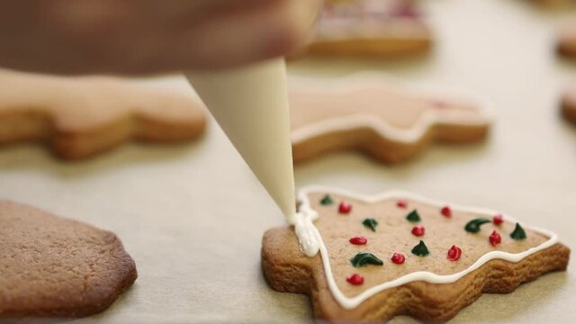 super close-up view of decoration homemade gingerbread Christmas cookies with food icing glaze, using bakery confectionery bag cone. glazing traditional winter holidays biscuit fir tree shape new year