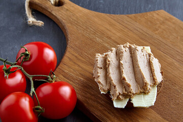 Homemade pate sandwich on wooden board on stone black table