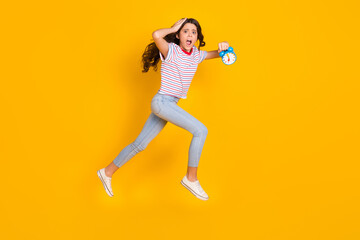 Fototapeta na wymiar Full body profile side of young girl amazed shocked go walk run jump hurry late missed clock time isolated over yellow color background