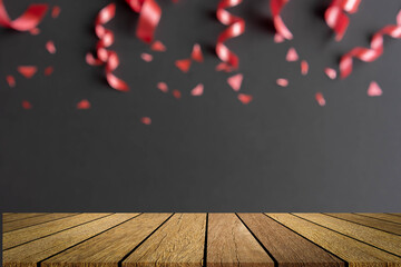 close up on group of red color of rolling ribbon and confetti on black background with wood table...