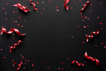 close up on group of red color of rolling ribbon and confetti on black background with copy space...