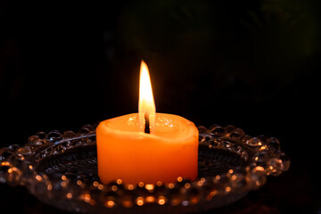 Flame of one white burning brightly wax candle on the dark black background