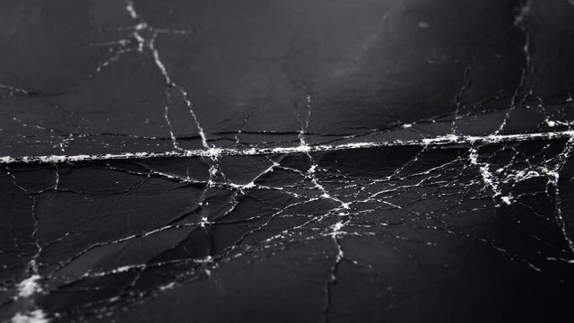 Worn black cardboard with wrinkles and cracks. Paper dark abstract background for design. Old packaging material. The concept of Halloween and horror movies. Macro. Slow rotation