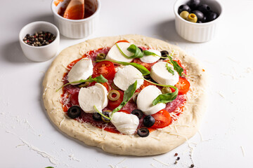Uncooked pizza, raw ingredients on a table