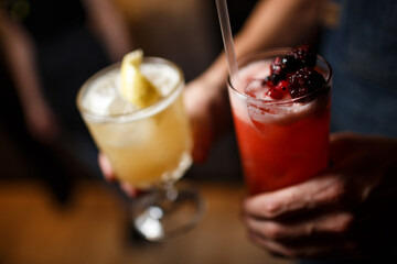 Glasses of yellow and red cocktails on tray in waiter hands in cafe. shallow depth of field