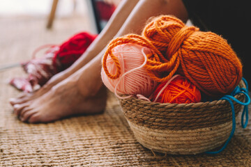 Woman sitting by basket of wool balls in living room