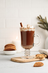 Cocoa or hot chocolate with marshmallows in a tall mug, on a wooden stand with cookies. Vertical, on a light background, with space