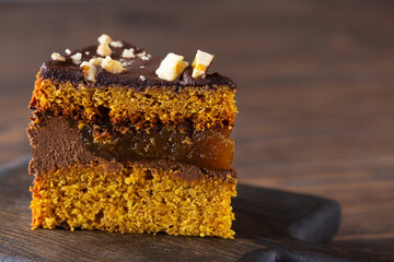 Piece of vegan chocolate pumpkin pie with nuts on a wooden board. Sugar, gluten and lactose free.