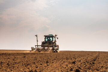 Fototapeta premium Tractor drilling seeding crops at farm field. Agricultural activity.