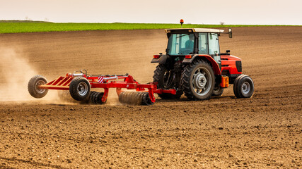 Fototapeta premium Tractor at agricultural farm field cultivating land