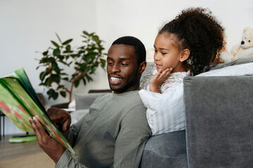 Young man telling story to daughter in living room
