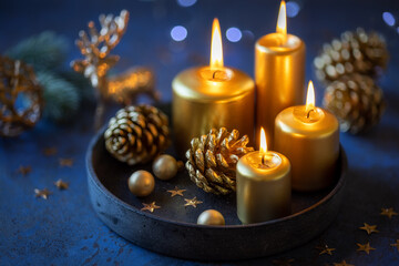 Christmas greeting card with lit golden candles, pine cones festive decorations against dark blue shabby background