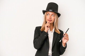 Young caucasian wizard woman holding wand isolated on white background looking sideways with...