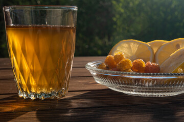 Kombucha in a glass glass, next to a plate of white raspberries and lemon