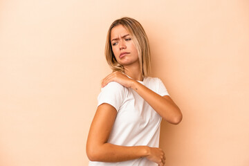 Young caucasian woman isolated on beige background having a shoulder pain.