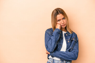 Young caucasian woman isolated on beige background who feels sad and pensive, looking at copy space.