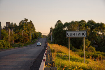 Rural road, sunset, car, pointer with the name of the locality