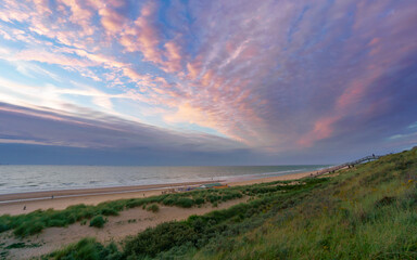 The sun sets over the North Sea near The Hague, casting pastel colors across the beach and sky.