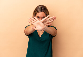 Young caucasian woman isolated on beige background doing a denial gesture