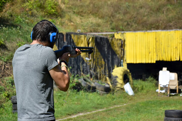 A young guy is trained in combat shooting from a shotgun.