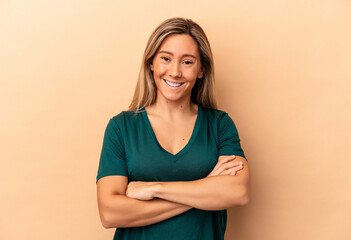 Obraz premium Young caucasian woman isolated on beige background who feels confident, crossing arms with determination.