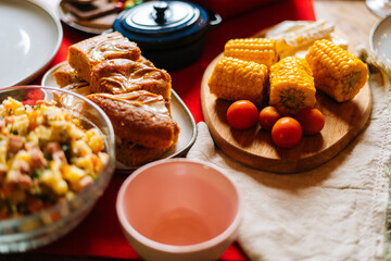 Close-up top view of delicious boiled yellow corn on feast dinner table during holiday friendly family party, selective focus. Concept of celebration New Year, Christmas, wedding, birthday.