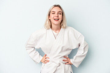 Young caucasian woman doing karate isolated on blue background laughing and having fun. © Asier