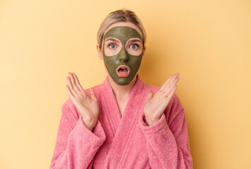 Young caucasian woman wearing face mask isolated on yellow background surprised and shocked.
