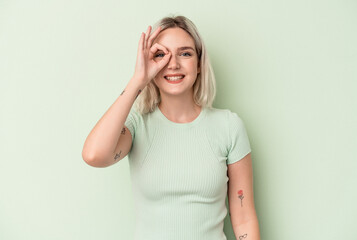 Young caucasian woman isolated on green background excited keeping ok gesture on eye.