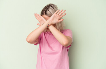 Fototapeta premium Young caucasian woman isolated on green background keeping two arms crossed, denial concept.