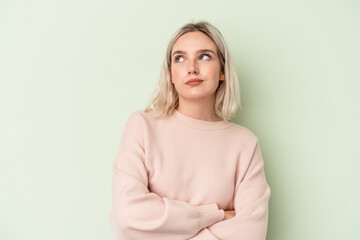 Young caucasian woman isolated on green background dreaming of achieving goals and purposes