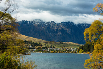 ニュージーランド　秋のクイーンズタウンのワカティプ湖の湖畔から見えるリマーカブルズ山脈とワカティプ湖と紅葉で色づいた木々