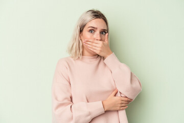 Young caucasian woman isolated on green background scared and afraid.