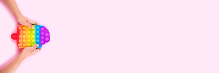 Banner with child's hands holding colored pop it anti-stress toy.