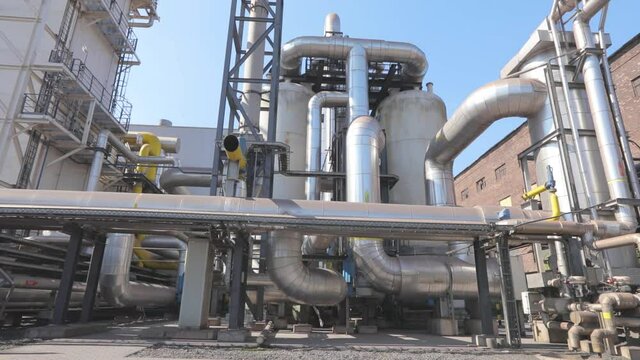 There are many large shiny pipes in the factory. Large metal shiny pipes. Industrial exterior
