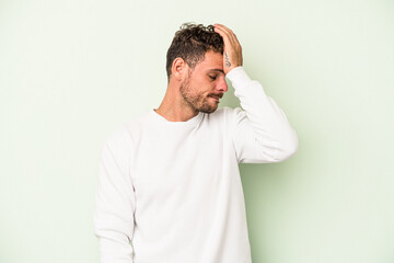 Young caucasian man isolated on green background forgetting something, slapping forehead with palm and closing eyes.