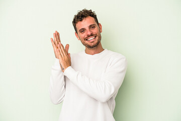 Young caucasian man isolated on green background feeling energetic and comfortable, rubbing hands confident.