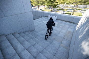 Woman freerider riding bike down city stairs