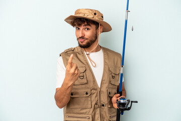 Fototapeta premium Young mixed race fisherman holding a rod isolated on blue background pointing with finger at you as if inviting come closer.